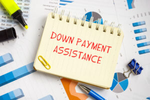 A notepad saying "Down payment assistance" laying on top financial papers with charts and graphs.